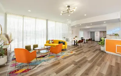 a living room with orange chairs and a yellow couch at The Sojourn Los Angeles - Sherman Oaks in Sherman Oaks