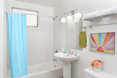 a bathroom with a blue shower curtain and a sink at The Sojourn Los Angeles - Sherman Oaks in Sherman Oaks