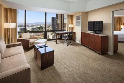 a hotel room with a couch and a bed and a television at The Westin Bonaventure Hotel & Suites, Los Angeles in Los Angeles