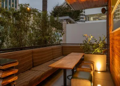 an outdoor seating area with a wooden table and chairs at SIRTAJ – Beverly Hills in Los Angeles