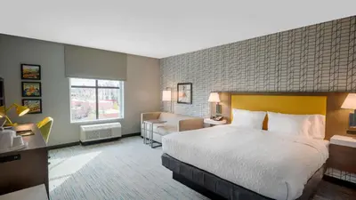 a hotel room with a large bed and a couch at Hampton Inn Riverside Downtown in Riverside
