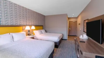 a hotel room with two beds and a flat screen tv at Hampton Inn Riverside Downtown in Riverside