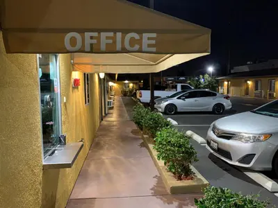 a white car parked in a parking lot next to an office at El Rey Inn - LAX in Gardena