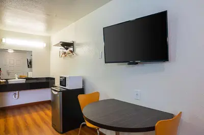 a room with a table and a flat screen tv on a wall at Motel 6-Ventura, CA - Downtown in Ventura