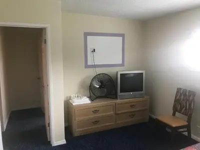 a room with a television on a dresser with a chair at All 8 Motel in Long Beach
