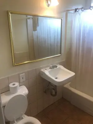a bathroom with a sink and a toilet and a mirror at All 8 Motel in Long Beach