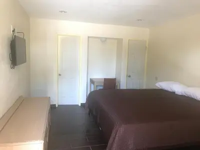 a bedroom with a bed and a desk and a tv at All 8 Motel in Long Beach