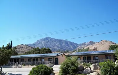 a building with a mountain in the background at Barewood Inn & Suites in Wofford Heights