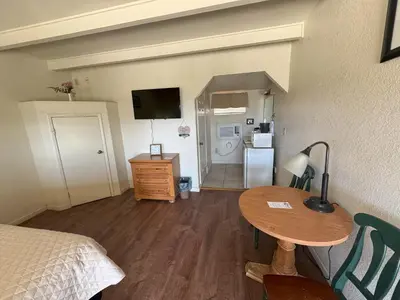 a room with a bed and a table and a refrigerator at Barewood Inn & Suites in Wofford Heights
