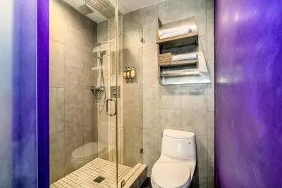 a bathroom with a toilet and a glass shower at The Moment Hotel in Los Angeles