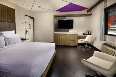 a bedroom with a bed and a desk and a tv at The Moment Hotel in Los Angeles