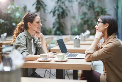 two women sitting at a table with a laptop at Motel 6 San Pedro, CA Port of Los Angeles in San Pedro