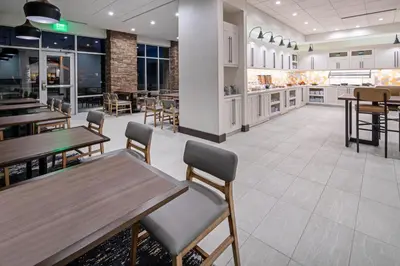 a restaurant with wooden tables and chairs and a kitchen at Hyatt Place Bakersfield in Bakersfield