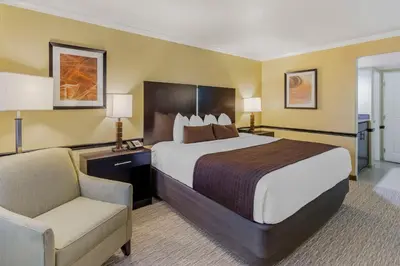 a hotel room with a large bed and a chair at Best Western Canoga Park Motor Inn in Canoga Park