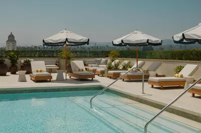 a pool with lounge chairs and umbrellas on a rooftop at L'Ermitage Beverly Hills in Los Angeles