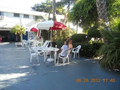 a group of people sitting at a table with an umbrella at Tradewinds Airport Hotel in Inglewood