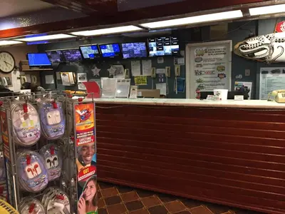 a restaurant with a bar with a counter and televisions at Tradewinds Airport Hotel in Inglewood