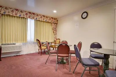 a waiting room with chairs and a table and a clock at Vagabond Inn Long Beach in Long Beach