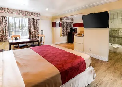 a hotel room with a large bed and a kitchen at Aqua Venture Inn in Long Beach