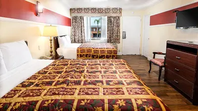 a hotel room with two beds and a flat screen tv at Aqua Venture Inn in Long Beach