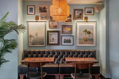 a restaurant with a leather bench and pictures on the wall at FOUND Hotels, Santa Monica, Series by Marriott in Los Angeles