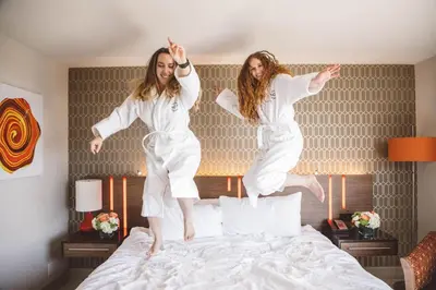 two girls jumping on a bed in a hotel room at Hotel Angeleno in Los Angeles