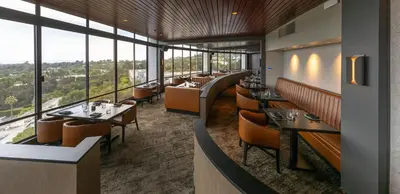 a restaurant with tables and chairs and large windows at Hotel Angeleno in Los Angeles