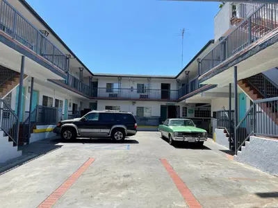 two cars parked in a parking lot in front of a building at Hollywood Guest Inn in Los Angeles
