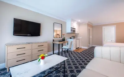 a living room with a couch and a tv on a wall at Beverly Hills Plaza Hotel & Spa in Los Angeles