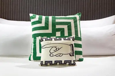 a green and white pillow sitting on top of a bed at Carlyle Inn in Los Angeles