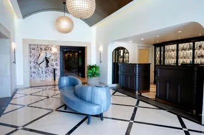 a living room with a blue chair and a piano at Hotel Amarano Burbank-Hollywood in Burbank