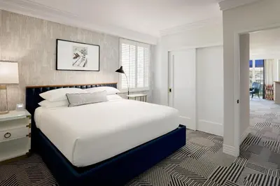 a bedroom with a large white bed and a lamp at Le Parc at Melrose in Los Angeles