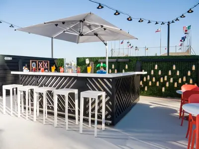 an outdoor bar with white stools and an umbrella at Le Parc at Melrose in Los Angeles