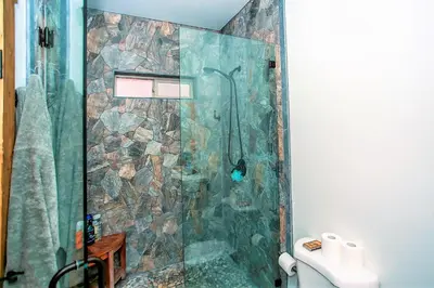 a bathroom with a shower with a stone wall at Alpine Chalet-1840 by Big Bear Vacations in Big Bear Lake
