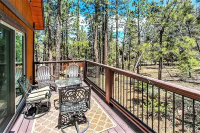 a porch with two chairs and a table on a deck at Alpine Chalet-1840 by Big Bear Vacations in Big Bear Lake