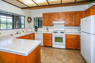 a kitchen with wooden cabinets and a white refrigerator at Breezy Estate-114 by Big Bear Vacations in Big Bear Lake