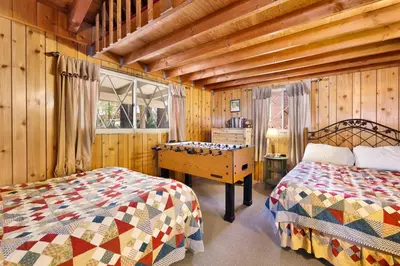 a bedroom with two beds and a wooden wall at Oriole Cottage-621 by Big Bear Vacations in Big Bear Lake
