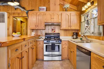a kitchen with wooden cabinets and a stove at Oriole Cottage-621 by Big Bear Vacations in Big Bear Lake