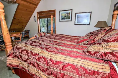 a bedroom with a bed with a red comforter at Knotty and Nice-177 by Big Bear Vacations in Big Bear Lake