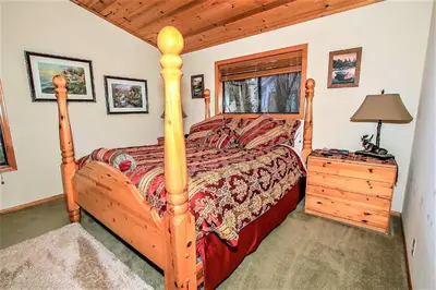 a bedroom with a wooden bed in a cabin at Knotty and Nice-177 by Big Bear Vacations in Big Bear Lake