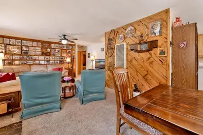 a living room with a wooden wall with a table and chairs at Popko's Place Resort Chalet by Big Bear Vacations in Big Bear Lake