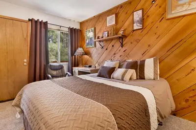 a bedroom with a bed and a wooden wall at Popko's Place Resort Chalet by Big Bear Vacations in Big Bear Lake