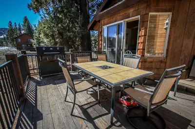 a wooden deck with a table and chairs on a cabin at Can't Bear to Leave-1156 by Big Bear Vacations in Big Bear Lake