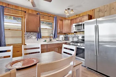 a kitchen with a table and a stainless steel refrigerator at Lakeside Family Cabin by Big Bear Vacations in Big Bear Lake