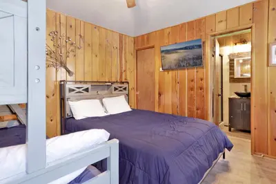 a bedroom with a bed and wooden walls at Lakeside Family Cabin by Big Bear Vacations in Big Bear Lake