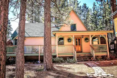 a small orange house with a porch in the woods at Kelley's Kabin-290 by Big Bear Vacations in Big Bear Lake