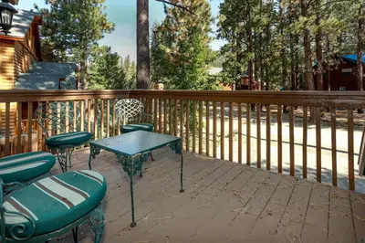 a table and chairs on a deck with a fence at Fawnskin Chalet-1826 by Big Bear Vacations in Fawnskin