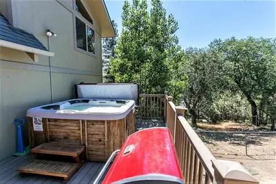 a hot tub sitting on a deck next to a house at Grandpas Axe-1775 by Big Bear Vacations in Big Bear Lake