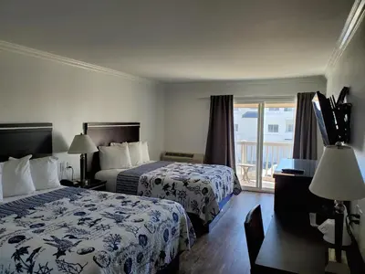 a hotel room with two beds and a balcony at Ocean Surf Inn & Suites in Huntington Beach