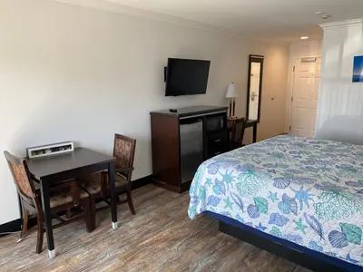 a hotel room with a bed and a desk and a television at Ocean Surf Inn & Suites in Huntington Beach